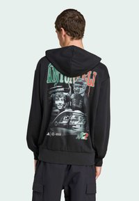 Sort hættepullover med et grafisk print på bagsiden, der viser flere billeder, herunder en bil og to ansigtstræk, med tekst i røde og grønne nuancer.
