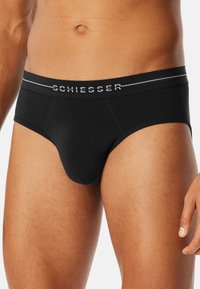 Svarta bomullsboxershorts med en slät textur, med en kontrasterande grå elastisk midjebok med "SCHIESSER"-logotyp och subtila accentlinjer.