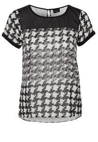 Blouse à manches courtes à motif pied-de-poule noir et blanc avec un empiècement noir transparent et un col arrondi.