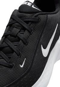 Zapatilla de running negra con parte superior de punto texturizado, logo de Nike en blanco, cordones planos y suela blanca con un diseño estampado.