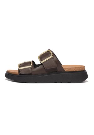 Brown leather slide sandal with two adjustable straps and gold hardware, cork footbed, and a thick black rubber sole.