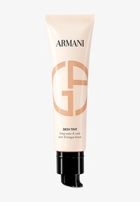 Tubo beige con un tappo a pompa nero, caratterizzato dal logo Armani e "Skin Tint" in testo nero, con una finitura liscia e lucida.