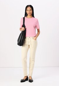 Ljusrosa kortärmad t-shirt, beige räfflade byxor med dragsko, svart axelväska och svarta ballerinaskor med nitar.