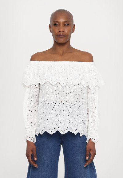 Blouse blanche à épaules dénudées avec un motif en broderie à œillets, bords festonnés et manches longues ; texture en coton lisse, coupe décontractée.