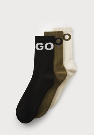 Set of three socks: black with white "GO," olive green, and cream, all ribbed texture. Each sock has a solid color with distinct lettering.