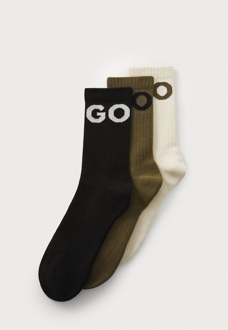 Sæt af tre sokker: sort med hvid "GO," oliven grøn, og creme, alle med ribbet tekstur. Hver sok har en ensfarvet farve med tydelig skrift.
