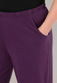 Pantalon en coton violet avec une taille élastique et des poches latérales, doté d'une texture lisse et d'un design droit.