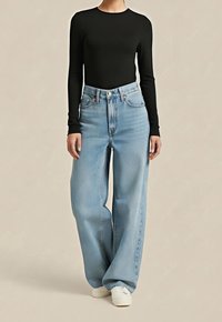 Černý top s dlouhým rukávem ve spojení s vysoko pasovanými širokými světle modrými džínami. Outfit doplňují bílé tenisky. Hladká látka, klasický design.