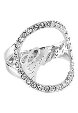 Sølvring med et hjerteformet omrids pyntet med små klare ædelstene og ordet "Guess" skrevet inde i hjertet.