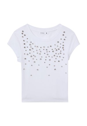 T-shirt bianco a maniche corte con una texture a coste, decorato con borchie metalliche argento sparse sul davanti.