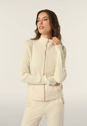 Cremfarbener Reißverschluss-Pullover mit strukturierten Kabelstrickärmeln, taillierter Passform, Stehkragen und gerippten Bündchen. Weicher, glatter Stoff.