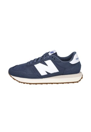 Zapatilla New Balance azul marino con logo blanco "N", pestaña blanca en el talón, suela de goma y diseño con cordones sobre un fondo blanco.