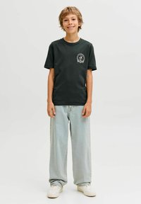 Tamsiai žalia medvilninė marškinėliai trumpomis rankovėmis, su apvaliu kaklu ir maža grafika kairėje krūtinės pusėje. Derinami su šviesiai mėlynais džinsais.