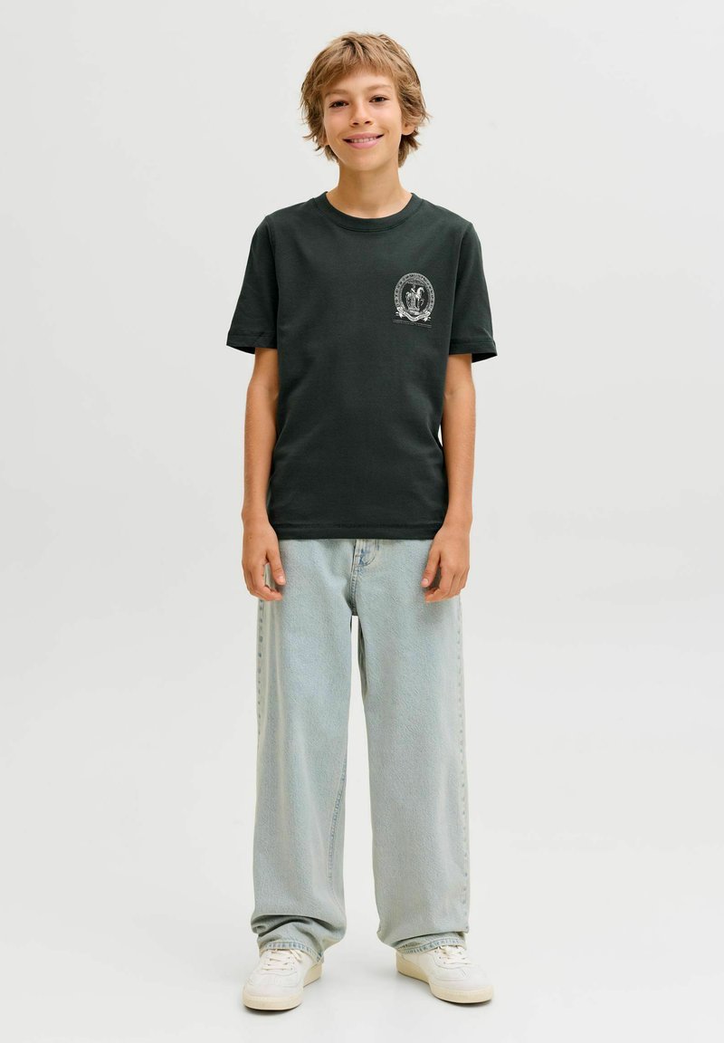 Tamsiai žalia medvilninė marškinėliai trumpomis rankovėmis, su apvaliu kaklu ir maža grafika kairėje krūtinės pusėje. Derinami su šviesiai mėlynais džinsais.