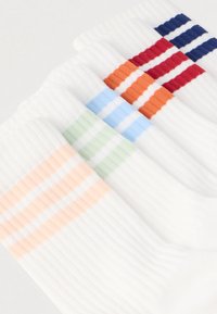 Fünf Paare weiße Socken mit bunten vertikalen Streifen in Orange, Blau, Rot, Grün und Pfirsich. Strukturierter, gerippter Stoff.