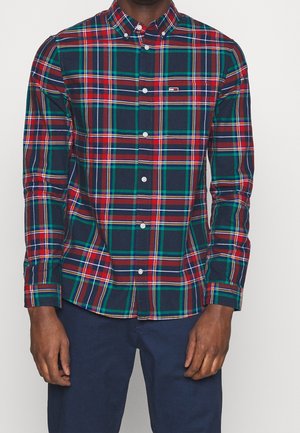 Camisa de botones con patrón de cuadros que presenta líneas en verde, rojo, azul marino y marrón. Mangas largas, cuello y detalle en el bolsillo del pecho. Material de algodón.