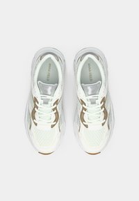 Άσπρα δερμάτινα αθλητικά παπούτσια με κορδόνια, ασημένιες και χρυσές λεπτομέρειες, στρογγυλή μύτη, μαλακό κολάρο και υφή στην σόλα. Λογότυπο "ANNA FIELD" στη γλώσσα.