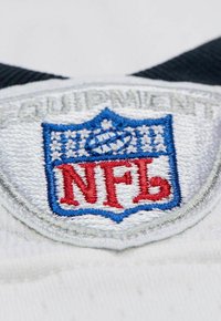 Nahaufnahme eines gestickten NFL-Wappenaufnähers mit einem blauen Football und roten "NFL"-Buchstaben auf weißem Stoff.