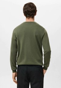 Sweter oliwkowy z okrągłym dekoltem i długimi rękawami, wykonany z miękkiego materiału. Charakteryzuje się minimalistycznym wzornictwem, dopasowanym krojem, bez widocznych wzorów.