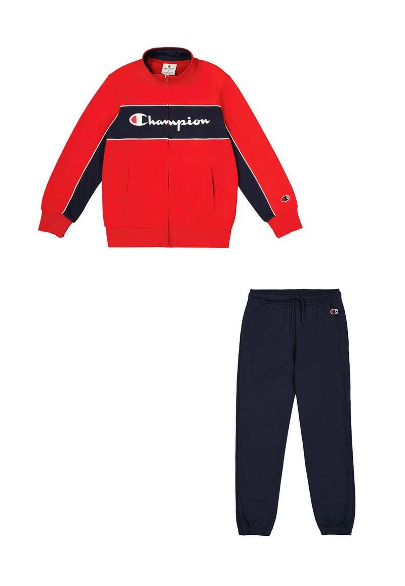 Giacca rossa con zip e dettagli blu navy, con logo "Champion" bianco, abbinata a pantaloni della tuta blu navy con vita elastica e logo.