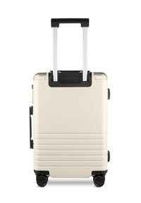 Hartschalentrolley in Cremefarbe mit horizontalen Rillen, schwarzen Akzenten, ausziehbarem Aluminiumgriff und vier Rädern für Mobilität.