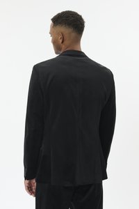 Mustast seemisnahast jakk valmistatud tikutopsi lõikega, tagaküljel ühe voldiga ja detailsete mansetinuppudega. Sile tekstuur ja sujuv siluett.