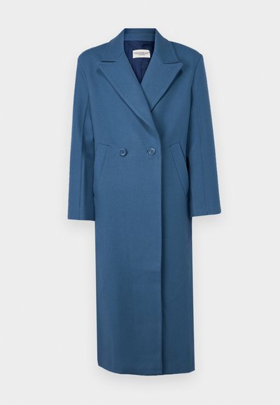 Dvojradový kabát v tmavomodrej farbe, s vykrojeným golierom, dlhými rukávmi a bočnými vreckami. Vyrobený z textilnej látky.