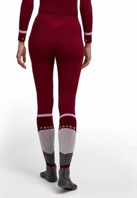 Bordowe legginsy termiczne z wysokim stanem oraz kontrastujące szaro-różowe skarpety za kolano z widocznie umieszczoną nazwą marki "FALKE".