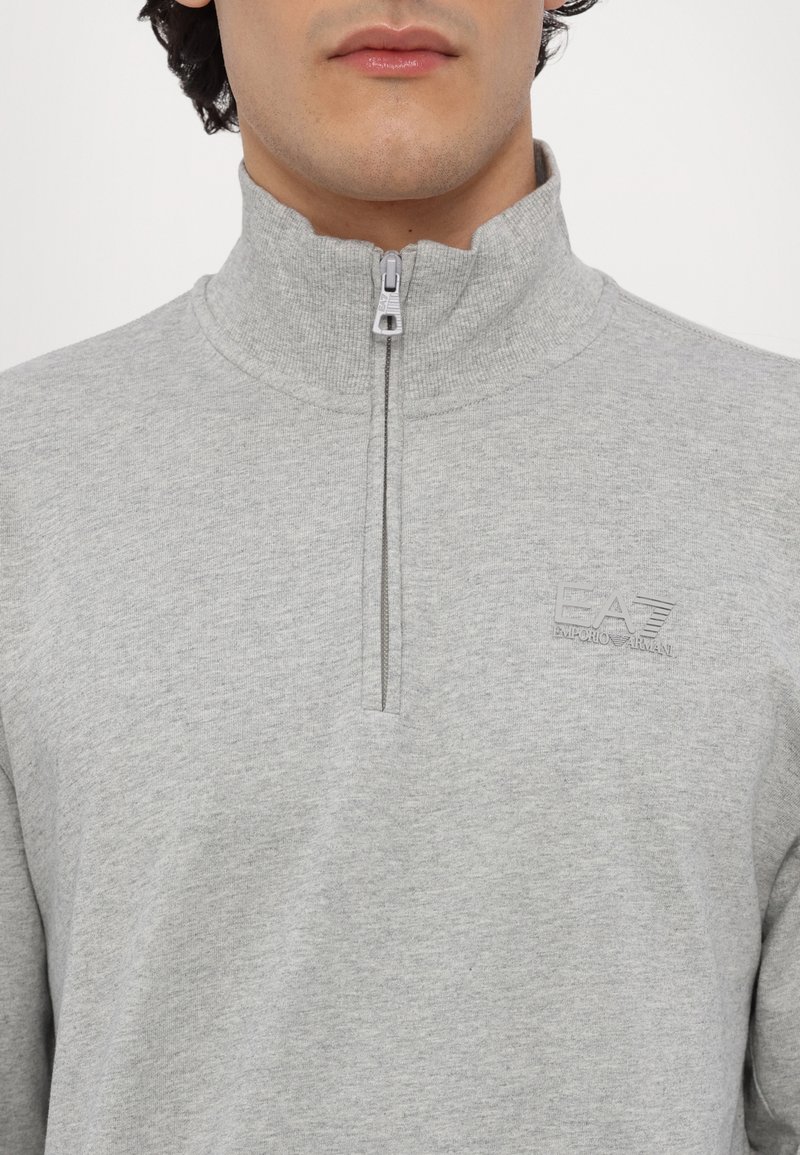 Sweatshirt zippé gris en tissu doux, doté d'un col montant et d'un petit logo EA7 en relief sur la poitrine.