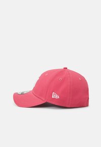 Punainen baseball-lippis, jossa on kaareva lippa ja joka on valmistettu puuvillasta. Etupuolella on brodeerattu logo ja sivussa ommeltu yksityiskohta.
