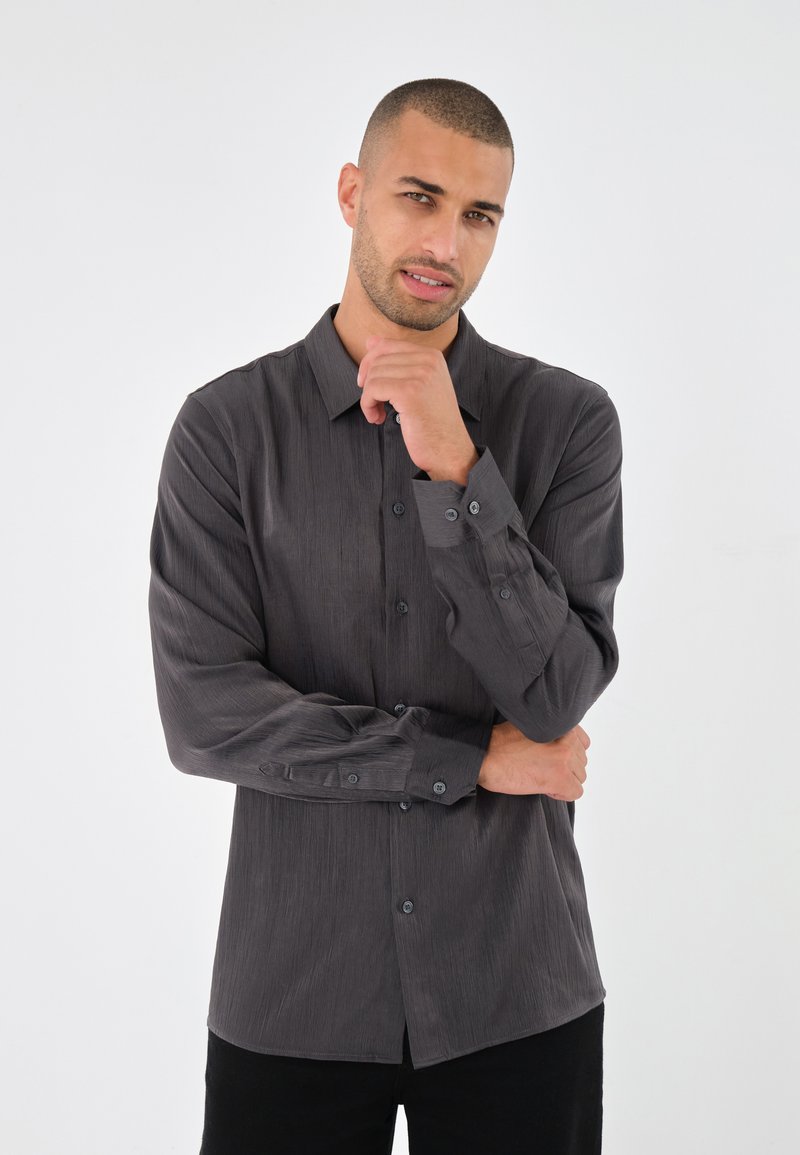 Gray long-sleeve shirt with a textured, slightly shiny finish. Features a button-down front and matching buttons on the cuffs. Casual fit.