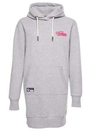Person wearing a gray hoodie dress with pockets, a navy and white varsity jacket, white socks, and white sneakers with maroon accents.
