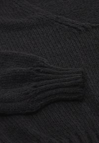 Maglione nero lavorato a maglia con un motivo testurizzato, maniche lunghe con polsini a coste e un tessuto morbido e spesso.