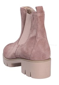 Bottine en daim rose clair avec panneau latéral élastique, semelle à gros crampons et languette à l'arrière.
