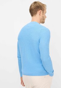 Lyseblå strikket sweater med lange ærmer, rund halsudskæring og ribbet kant. Teksturen er blød og glat med et diskret mønster.