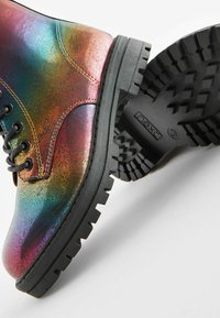 Varavīksnes iridescentas potītes zābaki, teksturēta sintētiska augšdaļa, melna gumijas zole ar dziļiem profilēm, un melna šņorēšana.