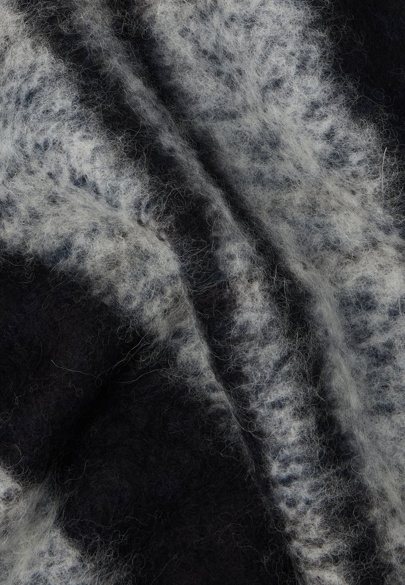 Tessuto di lana caratterizzato da una miscela di fibre blu scuro e bianche, con una texture morbida e soffice e motivi astratti che attraversano il materiale.