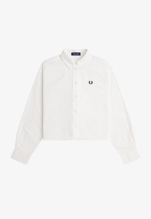 Chemise blanche courte à manches longues avec boutons sur le devant, col boutonné et petit logo de couronne de laurier sombre sur le côté gauche de la poitrine.