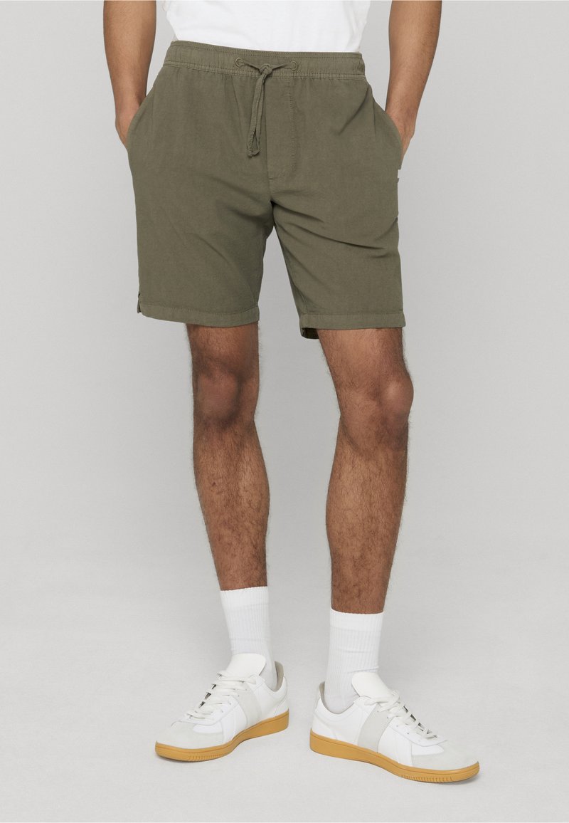 Shorts en coton vert olive avec une ceinture élastique et un cordon de serrage, dotés de poches latérales et d'ourlets pour une coupe décontractée.
