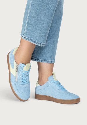 Person wearing light blue suede sneakers with beige accents and gum soles, paired with cropped light blue denim jeans.