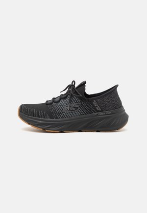 Czarno-szary sportowy but Skechers z teksturowaną dzianinową cholewką, sznurowanym zapięciem oraz grubą, amortyzowaną podeszwą z gumową podeszwą zewnętrzną, widoczne logo z boku.