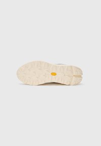 Footwear sole with a rugged, textured pattern. Light beige rubber material with a Vibram logo. Designed for traction on various surfaces.