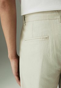 Lichtbeige linnen broek met een eenvoudig ontwerp, voorzien van een achterzak, subtiele textuur en een recht gesneden pasvorm.