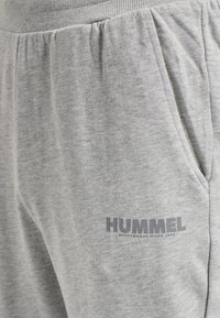 Graue Baumwollsweatpants mit einem gerippten Bund, Seitentaschen und einem in Dunkelgrau auf dem linken Oberschenkel aufgedruckten "HUMMEL"-Logo.