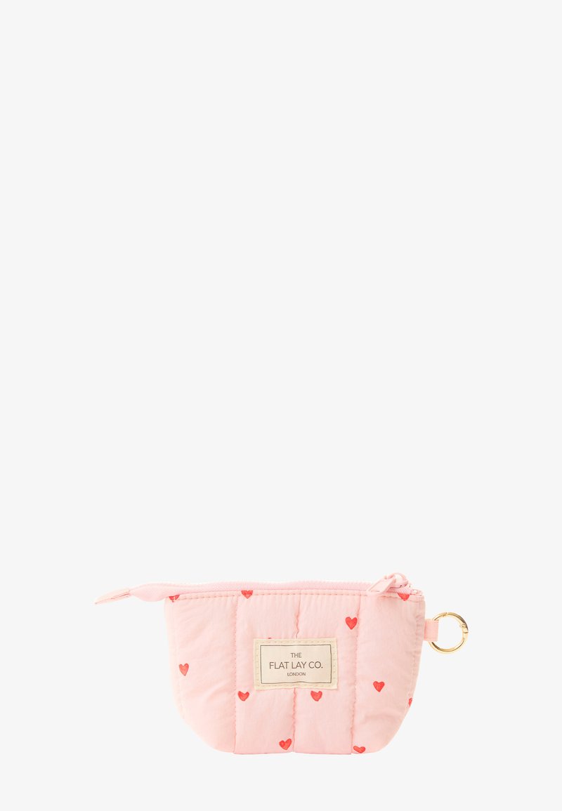 Petit pochette rose matelassée avec des cœurs rouges, fermeture éclair, porte-clés doré et étiquette "The Flat Lay Co. London" sur le devant.