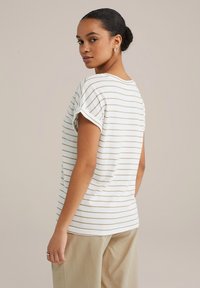 Lühikeste varrukatega valge särk õhukeste pruunide triipudega, lõdva lõikega, ümar kaelus ja üleskeeratud varrukad, kombineeritud beežide pükstega.