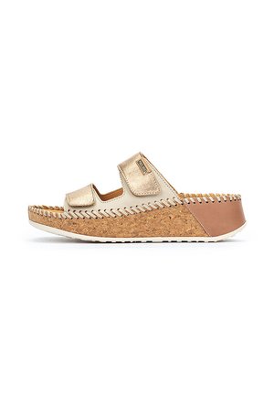 Sandale à semelle en liège avec une sangle beige mettant en valeur un accent métallique doré. Détails cousus le long des bords, accent de talon marron.
