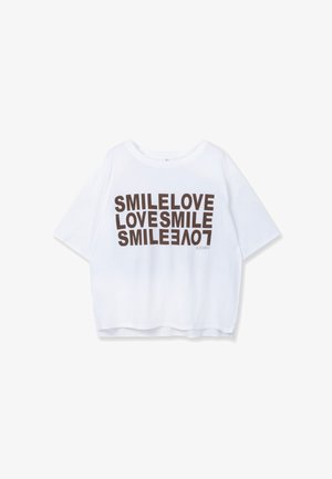 White cropped t-shirt made of soft fabric featuring bold brown text "SMILE LOVE LOVESMILE" in varied orientations. Rounded neckline, short sleeves.
