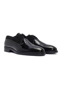Chaussures noires en cuir avec une finition brillante et des accents en daim. Bout arrondi, design à lacets et talon bas empilé.