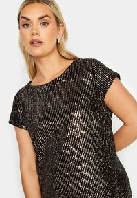 Musta lyhythihainen paita, joka on peitetty pystysuorilla koristekivillä luoden rakennekuvion. Pyöreä pääntie ja rento istuvuus kiiltävillä yksityiskohdilla.